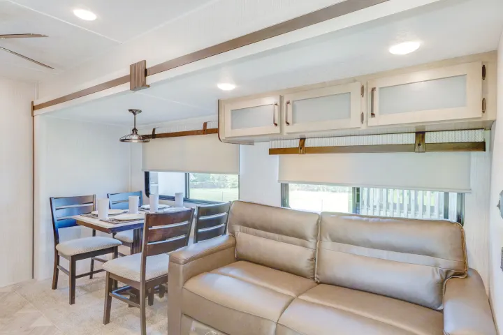 Comfortable RV rental living and dining space, featuring a set table and soft sofa seating.. Palomino Puma Park Trailer for Temporary Housing 2021