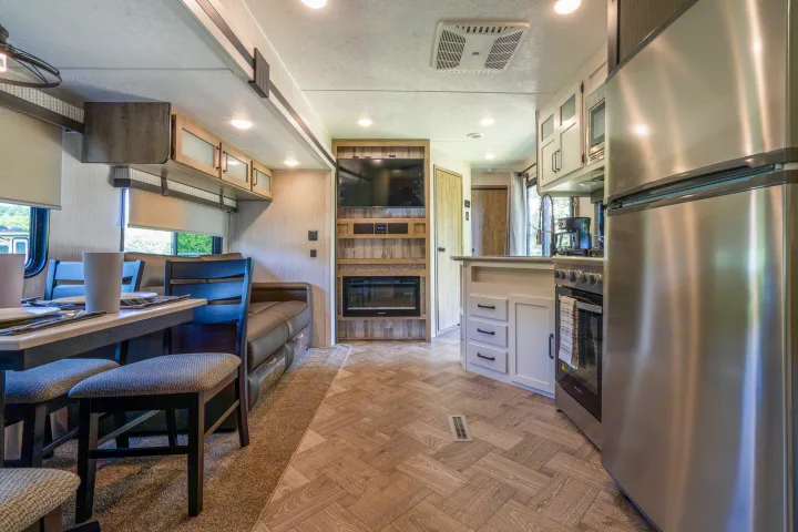 Spacious RV rental interior with kitchen, dining, and living area, featuring modern appliances and decor.. Palomino Puma Park Trailer for Temporary Housing 2021