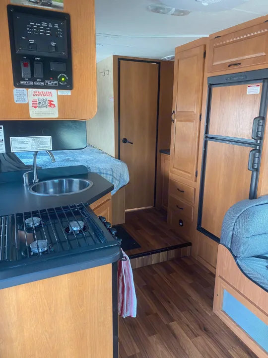 An RV rental's interior, featuring a compact kitchen with stove, sink, control panel, and a Dometic refrigerator.. Thor Motor Coach Four Winds Majestic 2013