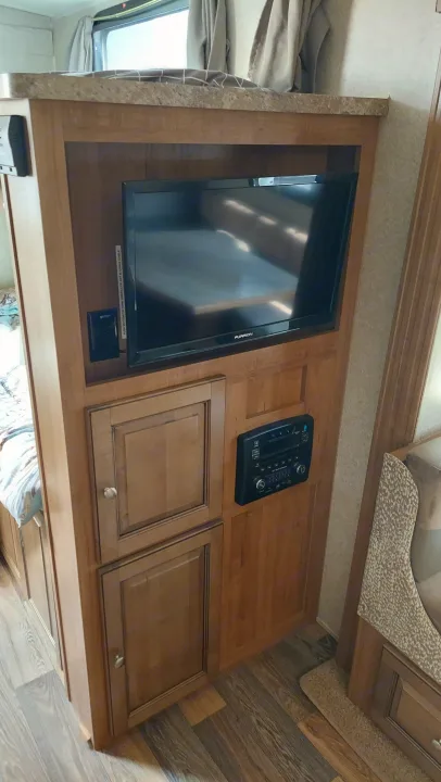 RV rental interior featuring a wooden entertainment center with a Furrion TV, media player, and storage cabinets.. Other Other 2016