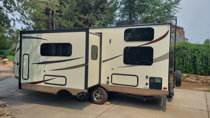 A beige travel trailer RV, with its slide-out extended, parked on a driveway. Ideal for your next rv rental adventure.. Other Other 2016