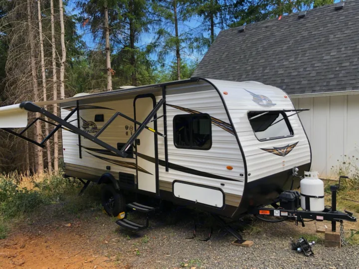 A white travel trailer RV rental, with an extended awning, parked on gravel. Perfect for outdoor camping adventures.. Jayco Jay Flight 2019