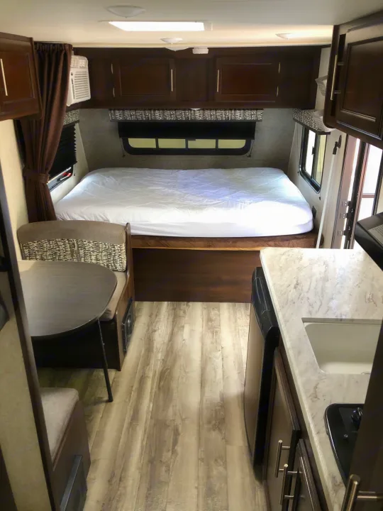 Bright RV rental interior: comfortable bed, dinette, and compact kitchen setup. Ideal for your next camper travel.. Jayco Jay Flight 2019