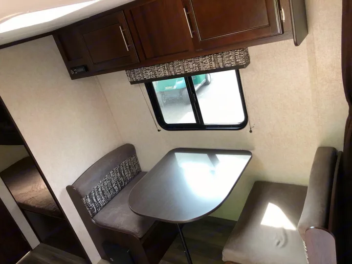 Inside an RV rental: a comfortable dinette area with a table, upholstered benches, and overhead cabinets.. Jayco Jay Flight 2019