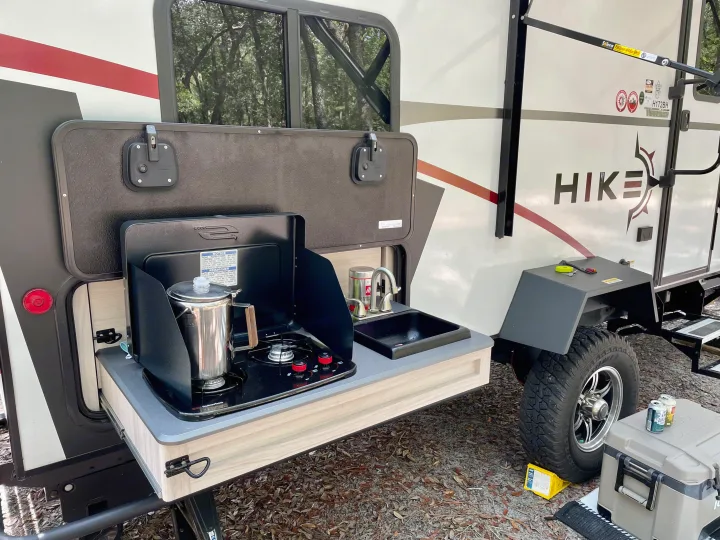 RV rental: Winnebago Hike travel trailer with an outdoor kitchen, featuring a stove, sink, and coffee percolator for camping.. Winnebago Hike 2021