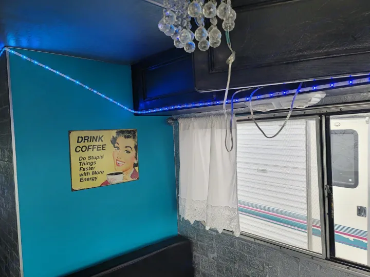 RV rental interior: A teal wall with a coffee sign, illuminated by vibrant blue LED strip lights, creating a unique space.. Chevrolet Other 1980