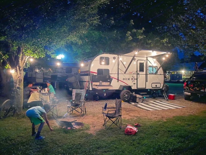 Cozy night at the campground with our RV rental, string lights, and a campfire. Family enjoys an evening outdoors.. Winnebago Hike 2021