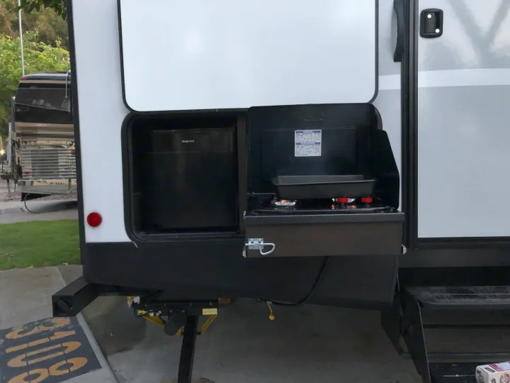 This RV rental features a convenient outdoor kitchen with a Hotpoint fridge and dual-burner cooktop, accessible via RV steps.. Keystone Bullet 2021