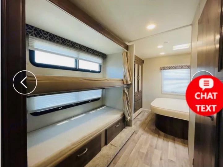 View inside an RV rental showing comfortable bunk beds, windows, and a curved sleeping area, ideal for family travel.. Jayco Redhawk 2018