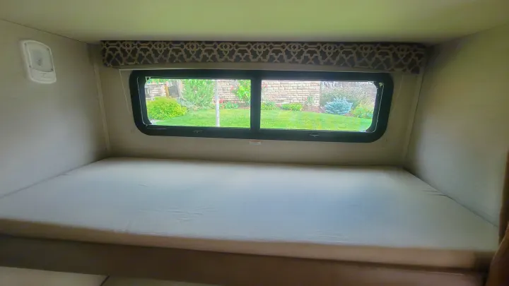 RV rental: Interior of a comfortable RV bunk bed area with a large window looking out to a green garden. Overhead light.. Jayco Redhawk 2018