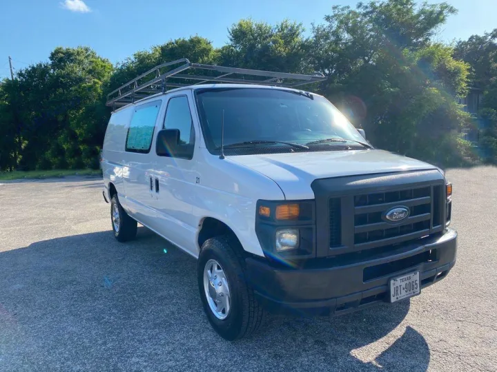 A white Ford cargo van with roof rack, parked outside. Excellent for work or as a DIY RV rental option.. Ford Ford E350 2011