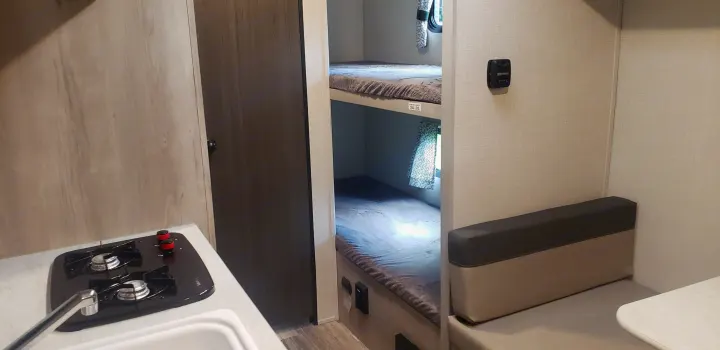 RV rental with a compact kitchenette, cozy bunk beds (250 lbs capacity), and a dinette area.. KZ Sportsmen 180BH 2021
