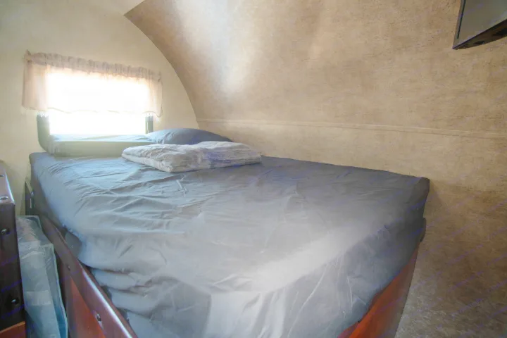 Cozy RV rental bedroom with a bed, pillow, and blanket by a bright window. A comfortable travel lodging option.. Forest River Salem Cruise Lite 2017