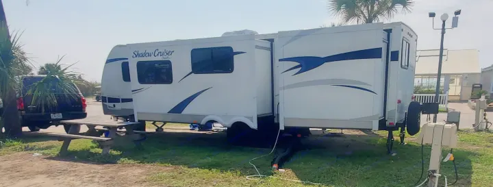 Shadow Cruiser RV rental set up at a sunny campground site with a picnic table and utility hookups. Ideal for outdoor stays.. Cruiser Rv Corp Shadow Cruiser 2012