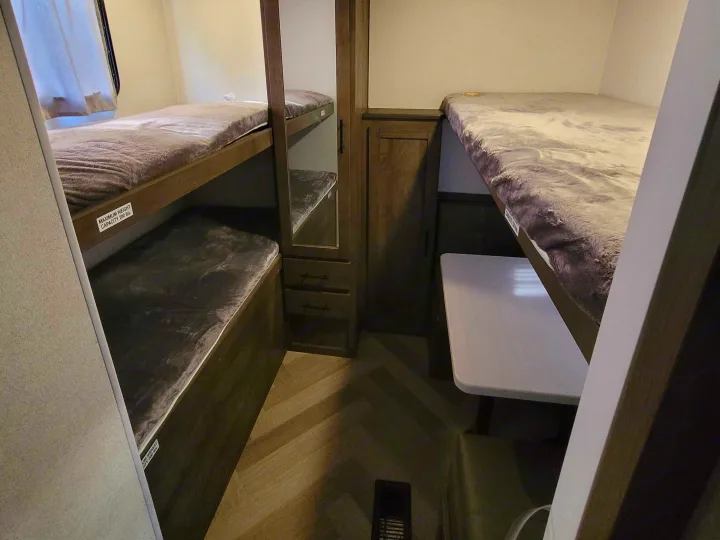 This RV rental offers cozy bunk beds, a central cabinet with mirror, and a small dining table for compact living.. Forest River Salem 2021
