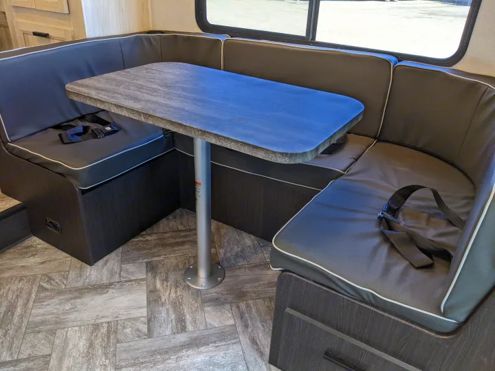 Comfortable U-shaped dinette with a stone-look table and seatbelts inside a spacious RV rental. Perfect for dining & travel.. Forest River Sunseeker 2025