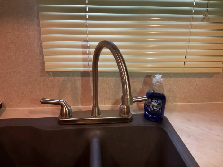 RV rental kitchen shows a stainless steel faucet, dark sink, Dawn dish soap, and window blinds.. Coachmen Clipper 2019
