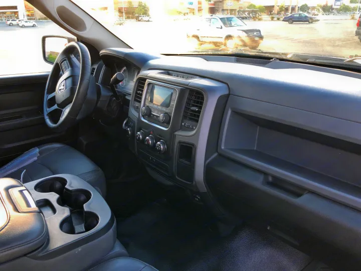 Driver's view from an RV rental truck: black dashboard, steering wheel, and bright parking lot visible through windshield.. Dodge 1500 2013