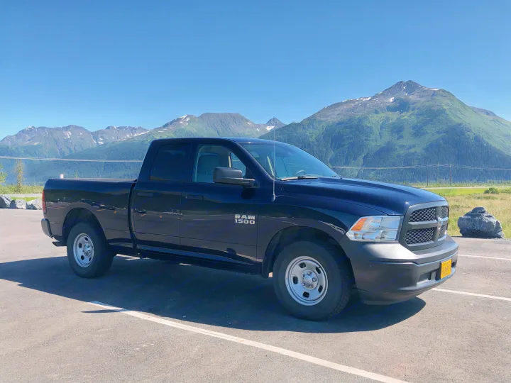 A black Ram 1500 pickup truck parked in front of mountains. Perfect for travel or to accompany an RV rental.. Dodge 1500 2013
