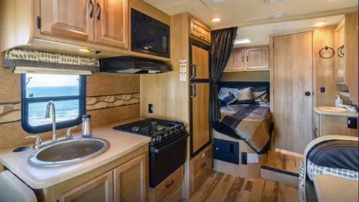 This cozy RV rental interior features a kitchen, bedroom, and bathroom, ideal for scenic travels by the ocean.. Coachmen Prism 2016
