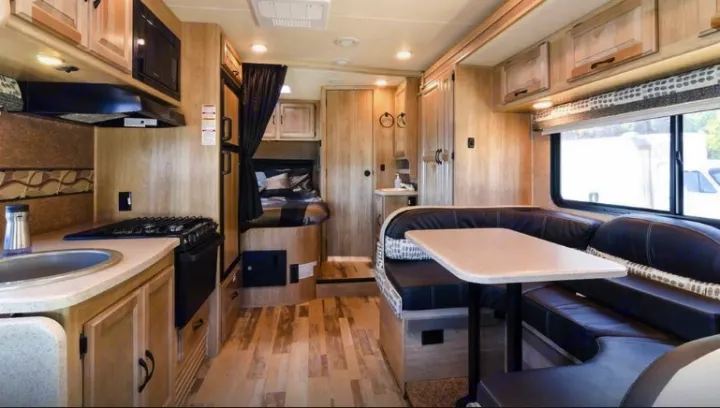 Spacious RV rental interior with full kitchen, U-shaped dinette, and a cozy bedroom area, ideal for comfortable travel.. Coachmen Prism 2016