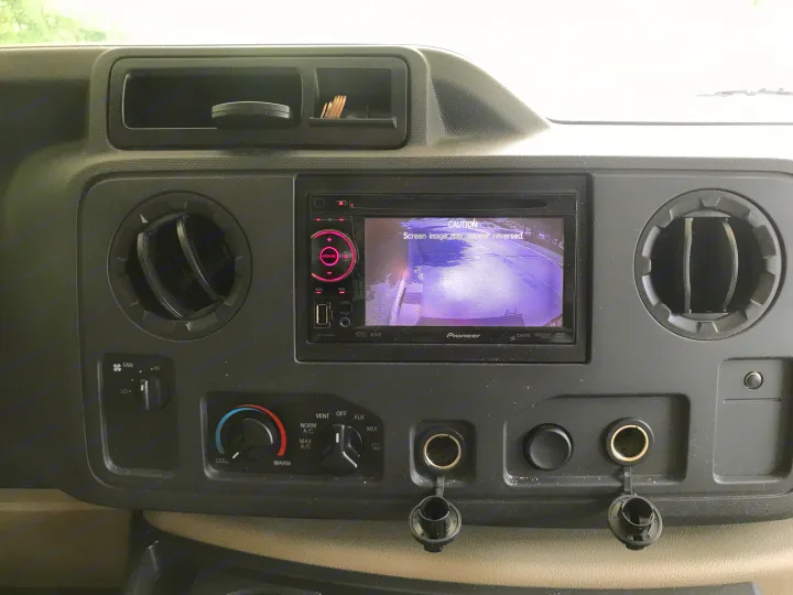 RV rental dashboard featuring a Pioneer rearview camera display, HVAC controls, air vents, and power outlets for convenience.. Thor Motor Coach Freedom Elite 2015