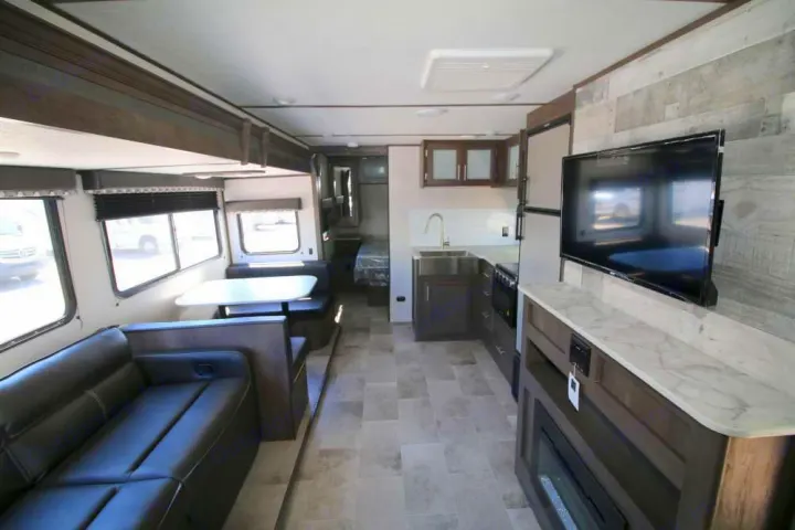 Spacious RV rental interior featuring a living area with couch, dinette, full kitchen, TV/fireplace, and a rear bedroom.. Coleman Other 2021