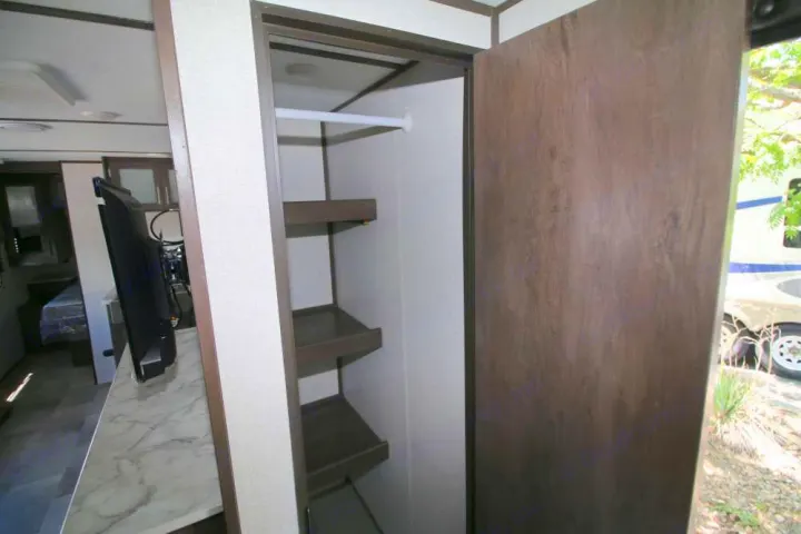 Inside this RV rental: a versatile storage area with a wardrobe rod and shelves, plus a mounted TV for entertainment.. Coleman Other 2021