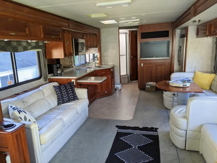 Experience comfort in this RV rental's inviting interior. Features a bright living room with white sofa, full kitchen, and dining area.. Fleetwood Pace Arrow 2007