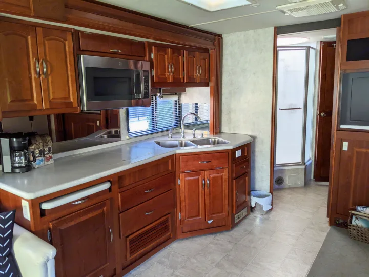 Inside this RV rental, a well-equipped kitchen features wood cabinets, stainless microwave, sink, and coffee maker, plus a shower.. Fleetwood Pace Arrow 2007