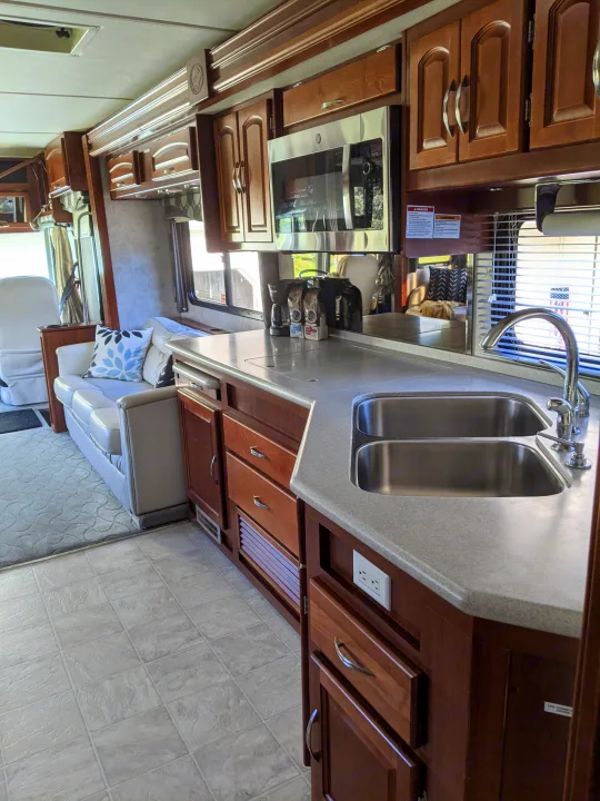 Spacious RV rental interior featuring a full kitchen with double sinks, microwave, wood cabinets, and living area.. Fleetwood Pace Arrow 2007