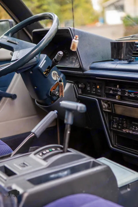 Interior of an RV rental: blue dashboard, steering wheel, and automatic gear shift ready for adventure.. Toyota Hiace 1985