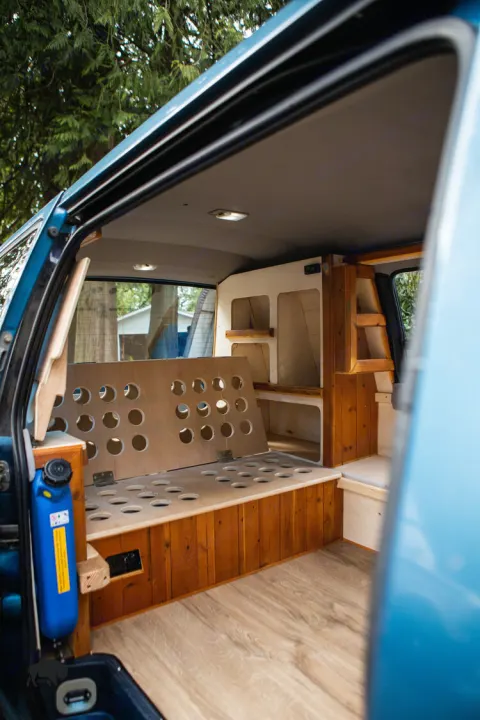Explore this cozy RV rental interior: custom wooden build-out, flexible seating/bed, and organized storage. Perfect for adventurers!. Toyota Hiace 1985