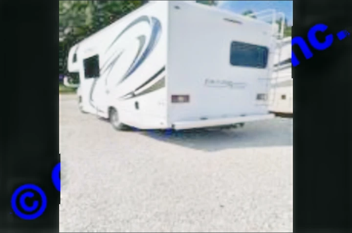 White recreational vehicle (RV) rental parked on a gravel lot, shown from the rear with a ladder.. Thor Motor Coach Freedom Elite 2019