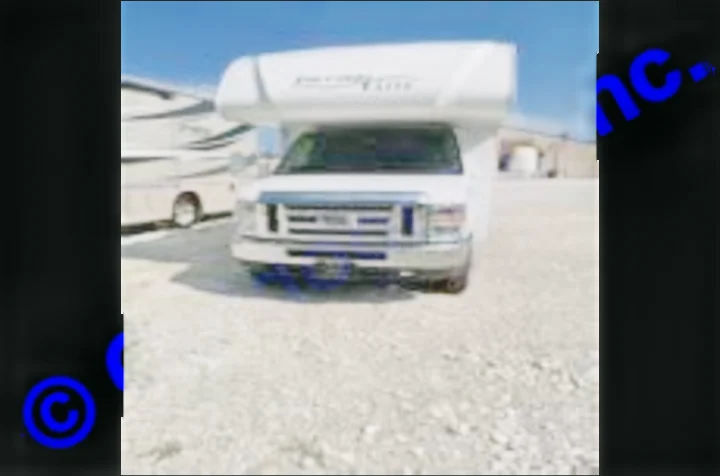 Front view of a white Class C RV rental, parked on a gravel lot under a clear sky, ready for your next adventure.. Thor Motor Coach Freedom Elite 2019