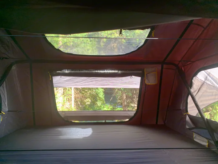 Interior of an RV rental rooftop tent. Enjoy nature views from this cozy camping setup with a comfy mattress.. Jeep Gladiator 2020