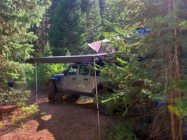 RV rental: Jeep Gladiator with roof tent & awning parked in a forest campsite, ready for adventure.. Jeep Gladiator 2020