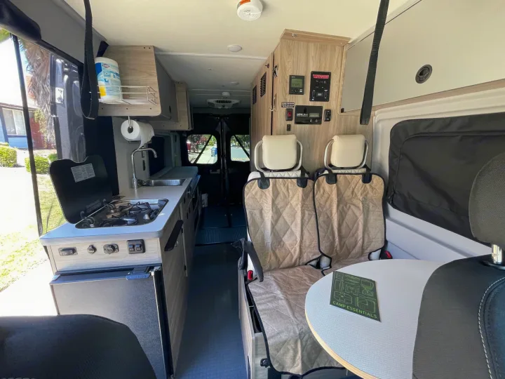 RV rental interior with a compact kitchen, control panel, and comfortable seating for your next adventure.. Winnebago Solis 2022
