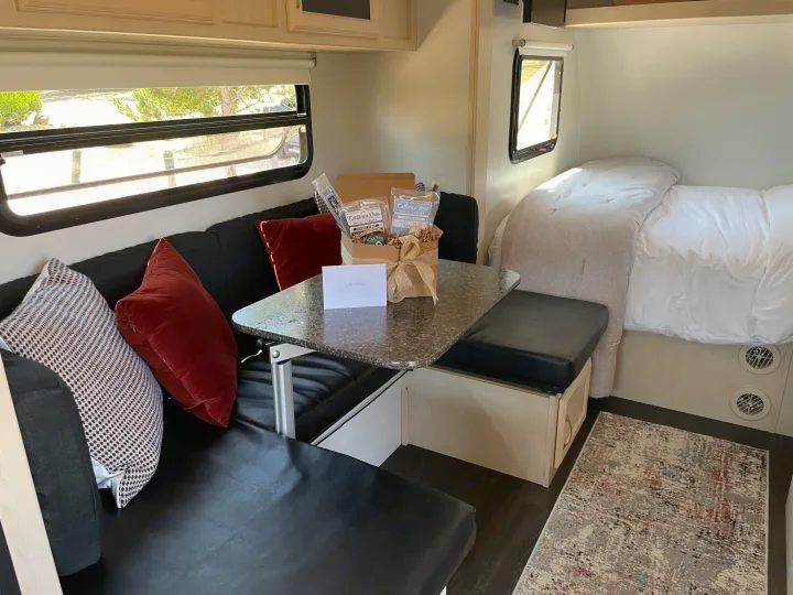 Inviting rv rental interior with a welcome snack gift box from Cattaneo Bros, dinette, and comfy bed.. Winnebago Minnie Winnie 2018