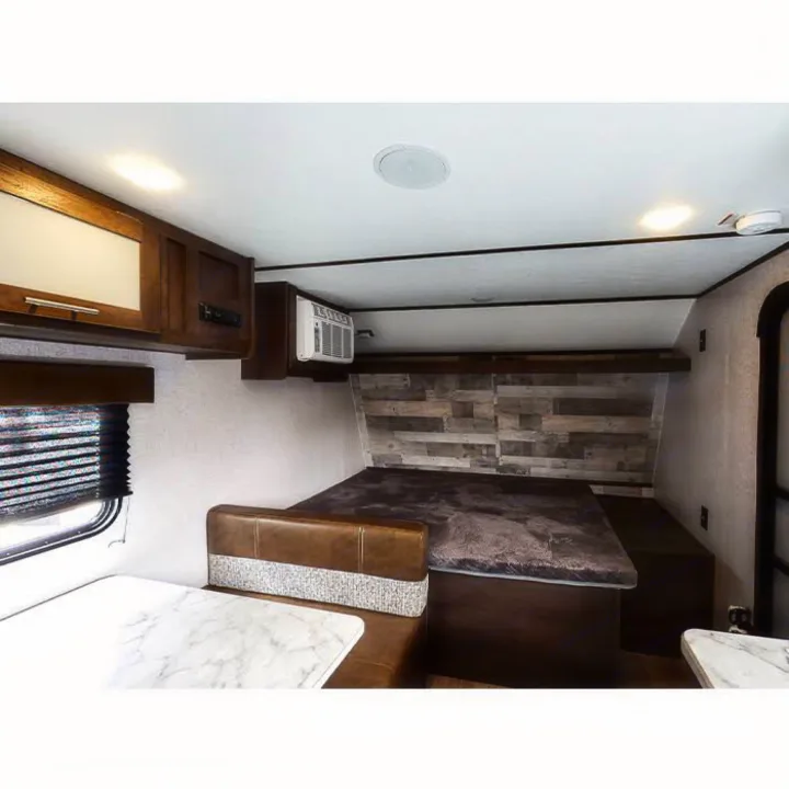 Step inside this cozy RV rental, featuring a bed with wood accent wall, dinette, and overhead cabinets. Ideal for travel!. Other Other 2021