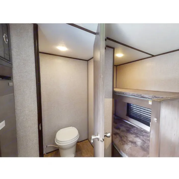 Inside an RV rental: compact bathroom with toilet and cozy bunk beds visible. Practical interior design for travel.. Other Other 2021