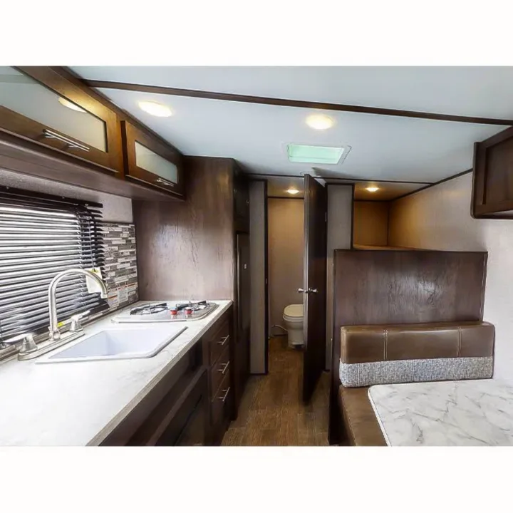 Interior of an rv rental, showcasing its compact kitchen, dinette, bathroom, and overhead bed.. Other Other 2021
