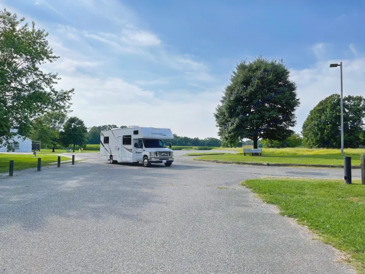 White RV rental parked in a spacious gravel lot, with green trees and a clear blue sky, perfect for your next adventure.. Other Other 2017