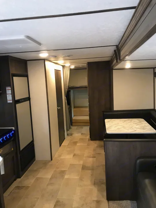 Spacious RV rental interior featuring a modern kitchen, dining booth, and bunk beds, ideal for comfortable travel.. Coleman 295QB 2021