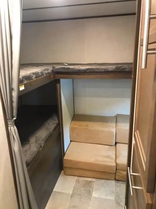 RV rental bunkhouse featuring an upper and lower bunk on the left, plus a top bunk and convertible sofa on the right.. Coleman 295QB 2021