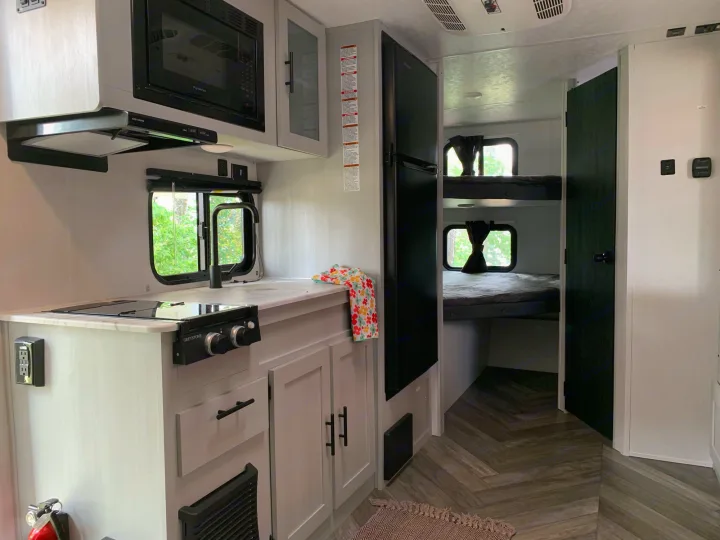 RV rental: Interior shows a light-colored kitchenette, black refrigerator, and bunk beds with dark curtains.. Forest River Salem 2021