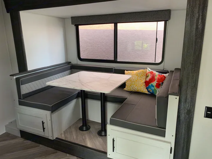 This RV rental offers a well-appointed dinette area with U-shaped cushioned seating, a central table, and storage cabinets.. Forest River Salem 2021