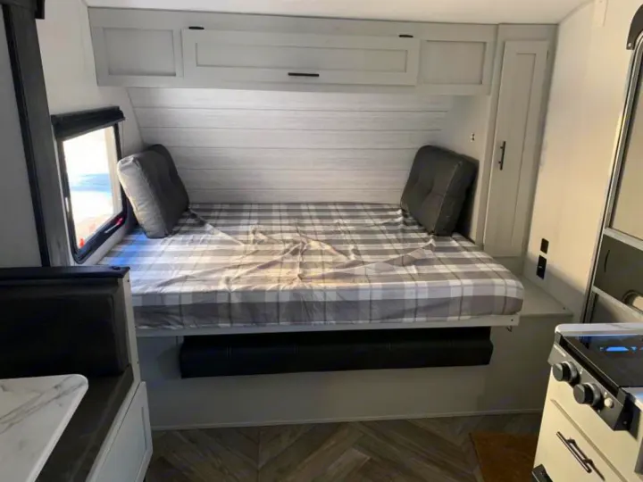 This RV rental offers a cozy bunk bed with plaid bedding, overhead storage, and compact kitchen space.. Forest River Salem 2021