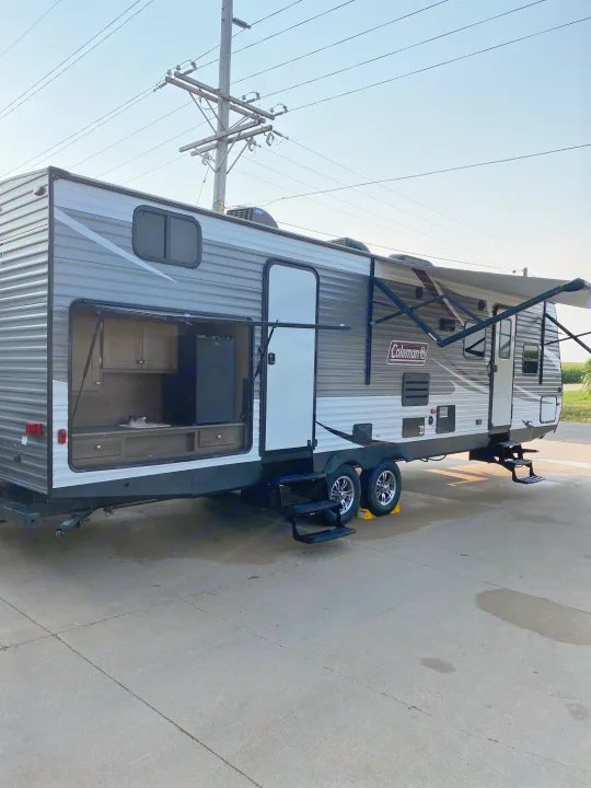 Travel trailer RV rental with open outdoor kitchen and extended awning on concrete. Ready for adventure!. Dutchmen Coleman 2019