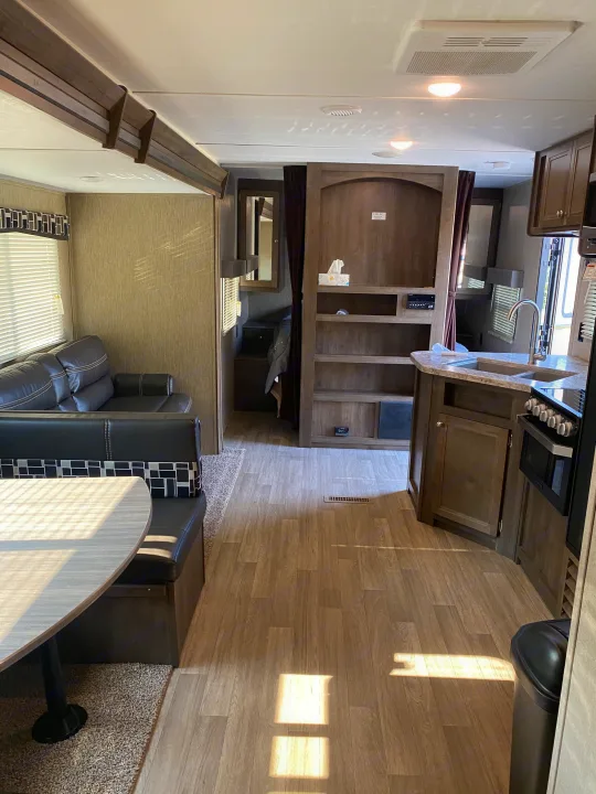 Spacious RV rental interior with a cozy living area, dining booth, and functional kitchen. Ready for travel.. Dutchmen Coleman 2019